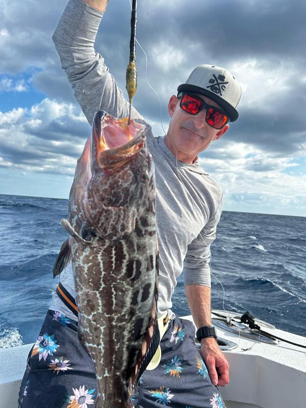 Angler holding a grouper on Cancun fishing boat